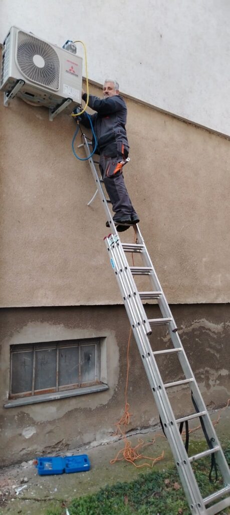 Montaža inverter klima uređaja u stanu – prikaz majstora koji pažljivo instalira unutrašnju jedinicu na zidu, uz profesionalnu opremu.